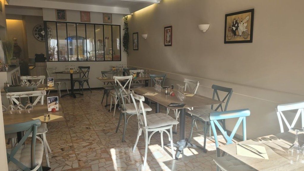 La salle : tables dressées, chaises blanches et carrelage ancien