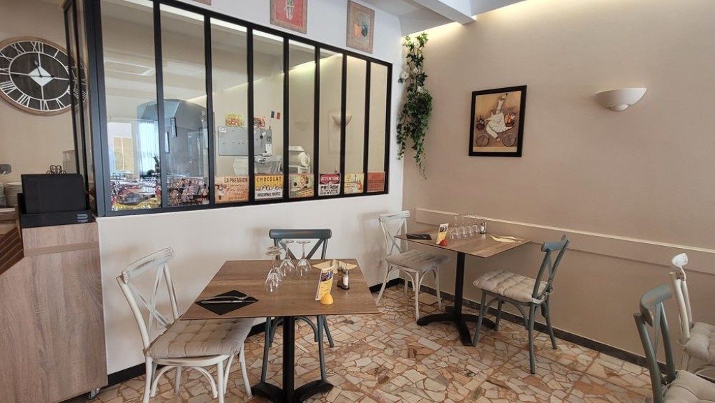 La salle vue depuis le fond, avec sa verrière et ses tables carrées